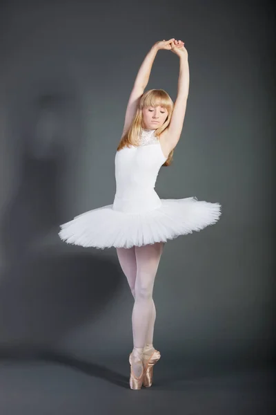 年轻的女芭蕾舞蹈家蹑手蹑脚地走过灰色的背景 — 图库照片