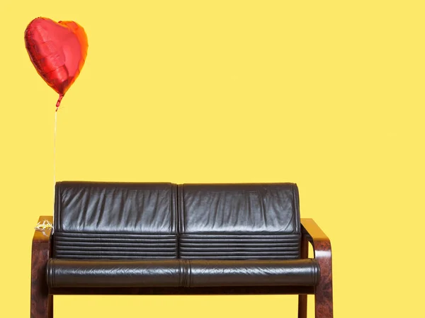 Balon Kształcie Serca Przywiązany Sofy Żółtym Tle — Zdjęcie stockowe