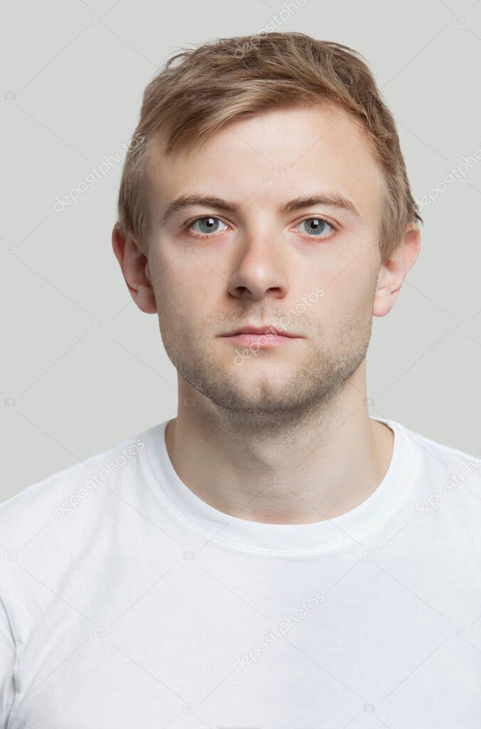 Portrait of serious young man in t-shirt against gray background