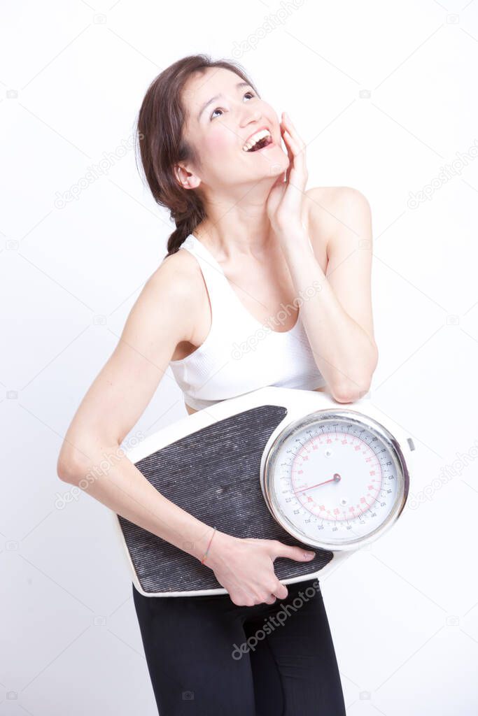 Cheerful Asian woman with weight scale against white background