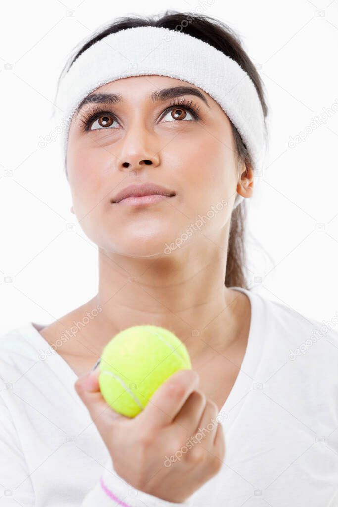 Young ambitious female tennis player looking up over white background