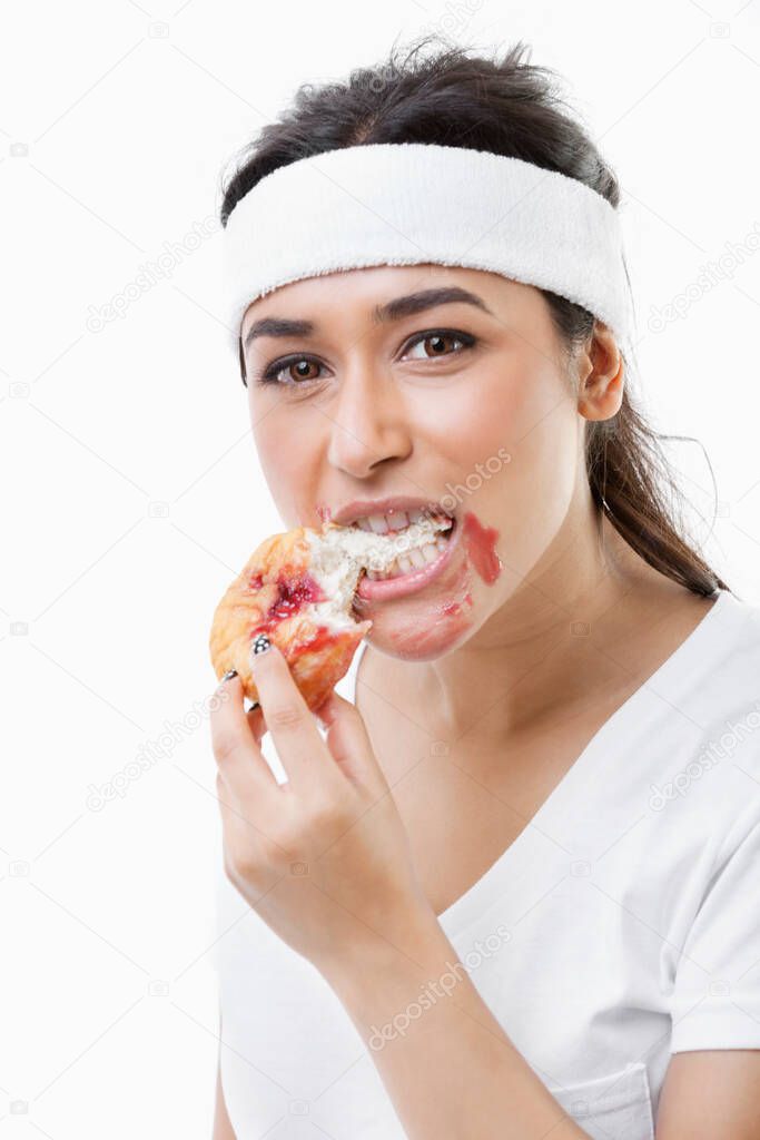 Portrait of young woman eating donut over white background