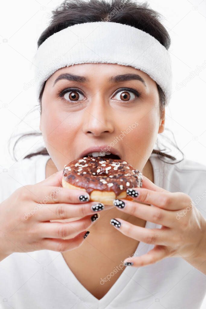 Portrait of young Asian woman eating donut over white background