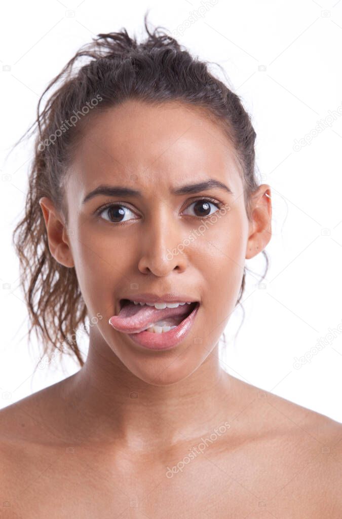 Portrait of young Mixed Race woman sticking out her tongue against white background