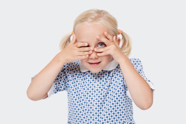 Beyaz arka planda parmaklarının arasından gözetleyen genç bir kızın portresi.