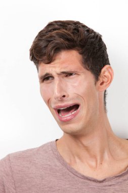 Korkmuş genç adam beyaz arka planda ağlıyor.
