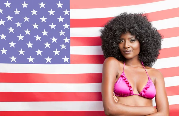 穿着比基尼站在美国国旗前的时髦年轻女子的画像 — 图库照片