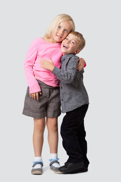 在白人背景下拥抱妹妹的快乐的小男孩的画像 — 图库照片