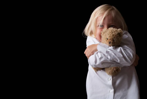 可爱的金发姑娘抱着黑黑的背景的泰迪熊 — 图库照片