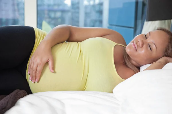 若いです妊娠中の女性は笑顔でベッドの上で自宅で — ストック写真