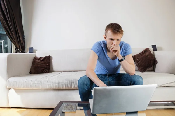 Homem Pensativo Usando Laptop Enquanto Sentado Sofá Casa — Fotografia de Stock