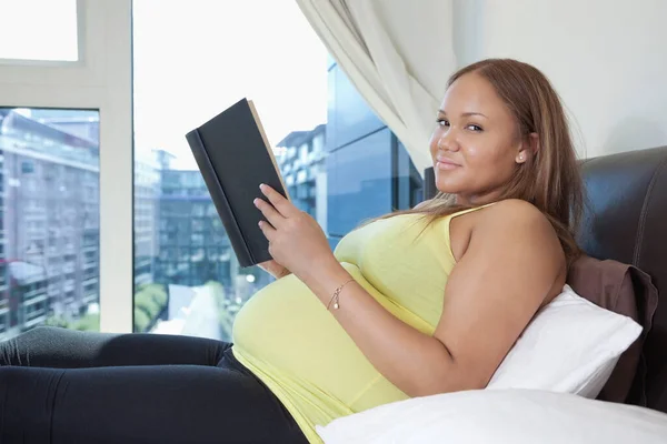 若いです妊娠中の女性の肖像とともに本リラックスオンベッド ホーム — ストック写真