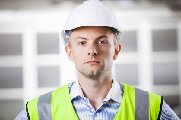 Портрет уверенного молодого архитектора в каске и бронежилете