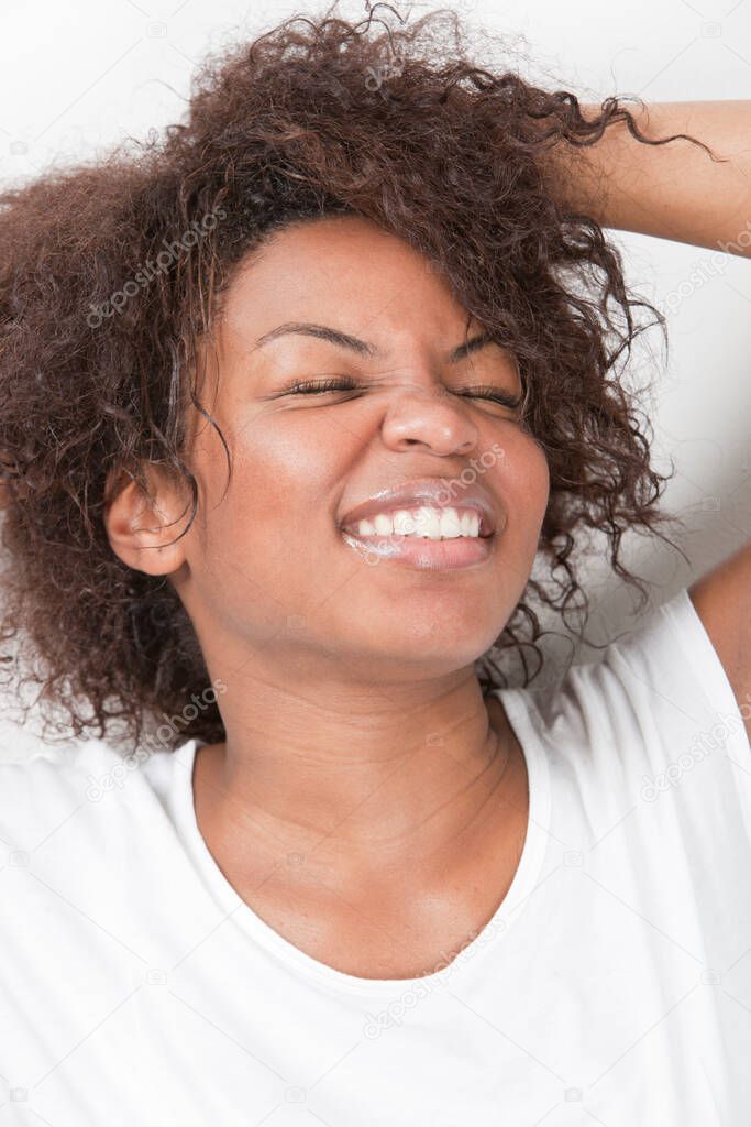 Excited young African American woman with hands in hair smiling against white background