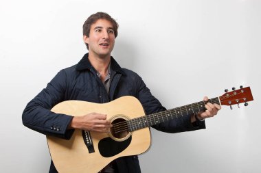 Beyaz arka planda imza atarken gitar çalan genç adam