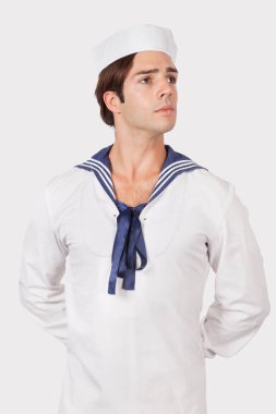 Denizci üniformalı düşünceli genç adam gri arka plana bakıyor.