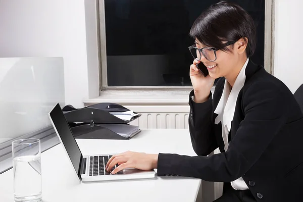 Widok Boku Młodej Bizneswoman Pomocą Laptopa Telefonu Komórkowego Biurze — Zdjęcie stockowe