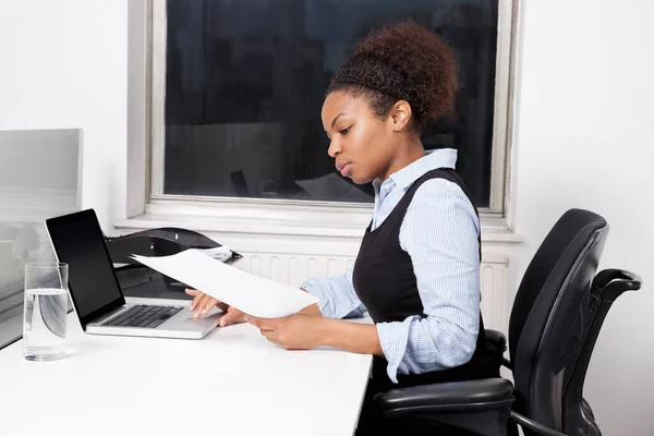 办公室使用笔记本电脑的持有文件的年轻女商人的侧视图 — 图库照片