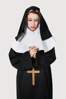 Gri arka plan için dua eden genç bir rahibe