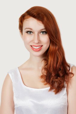 Gri arka planda gülümseyen güzel bir genç kadının portresi.