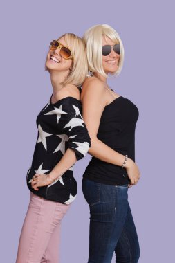 İki güzel çok ırklı kadının arka arkaya mor arka planda portresi.