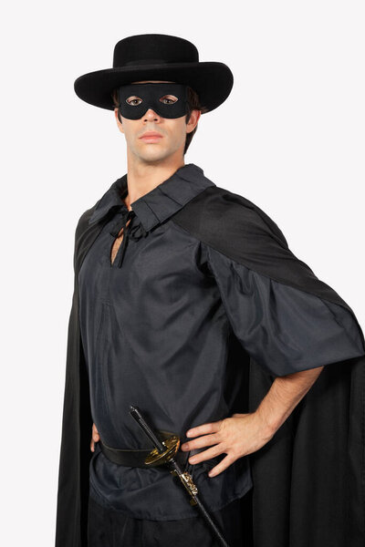 Portrait of young man dressed as Zorro against gray background