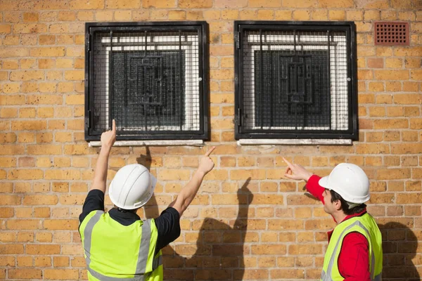 Rear View Two Male Workers Hardhats Pointing Windows — Stock Photo, Image