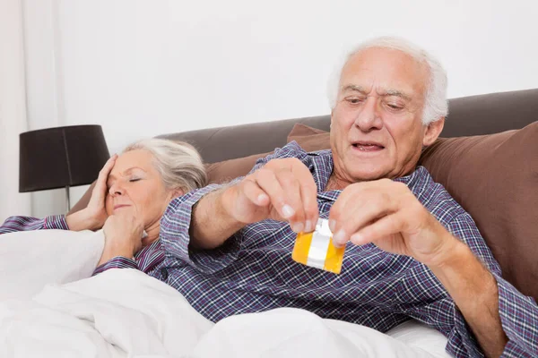 Elderly Man Tearing Condom Packet While Spouse Sleeping Bed — Stock Photo, Image