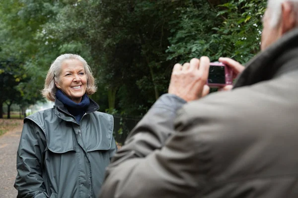 快乐的老年妇女在公园被丈夫拍照 — 图库照片