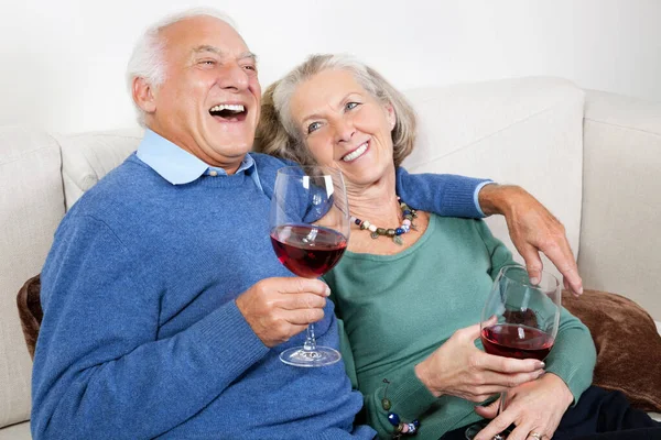 Casal Sênior Feliz Com Copos Vinho Tinto Enquanto Sentado Sofá — Fotografia de Stock