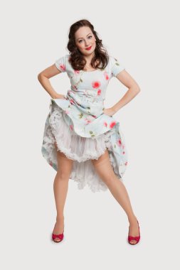 Güzel bir genç kadının portresi, elleri kalçalarında beyaz arka planda.