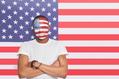 Amerikan bayrağına karşı boyalı yüzü olan kendinden emin bir gencin portresi.