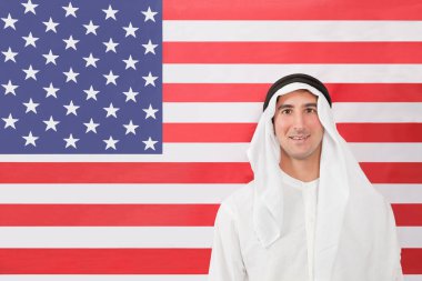 Geleneksel giysiler içinde Amerikan bayrağına bakan bir Arap portresi.