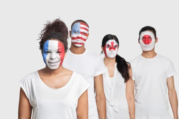 脸上挂着不同国旗的多民族朋友站在白色背景下的画像 — 图库照片