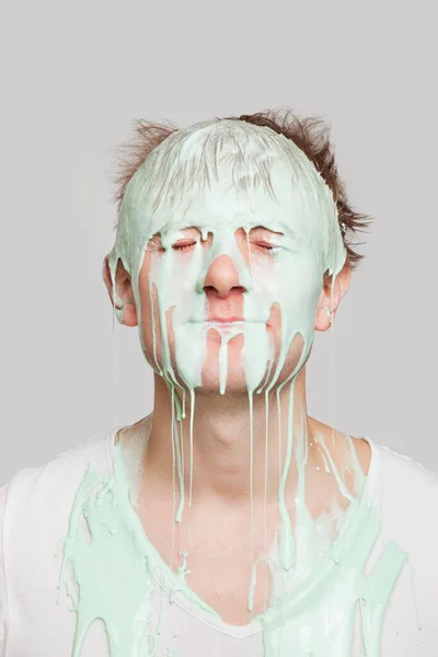 灰色の背景に若い白人男性の顔を滴下ペイント — ストック写真