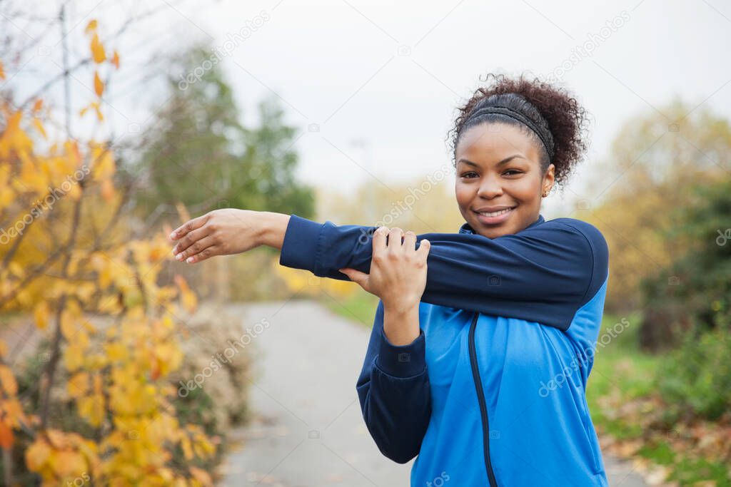 Portrait of young woman stretching in park