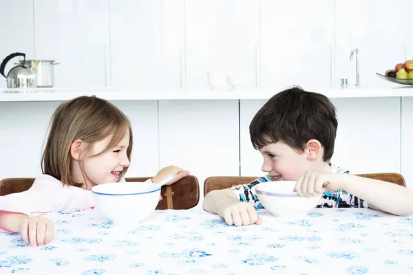 Αγόρι Και Κορίτσι Κάθονται Στο Τραπέζι Της Κουζίνας Τρώγοντας Δημητριακά — Φωτογραφία Αρχείου