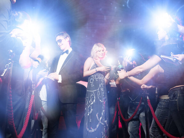 Celebrity couple arriving a premiere with paparazzi cameras and flashes