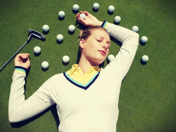 年轻美丽的女人躺在球道上和高尔夫球球在一起 — 图库照片