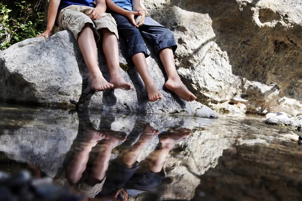 Nehir Kenarındaki Kayada Oturan Iki Çocuk — Stok fotoğraf