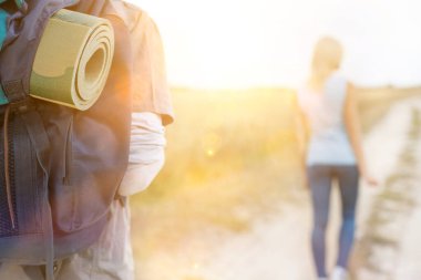 Erkek yürüyüşçü sırtında bir kadınla ön planda yürüyor.