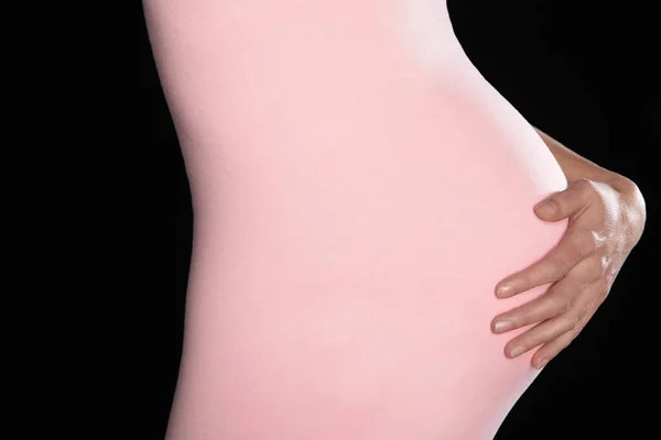 Pregnant woman in body suit holding abdomen
