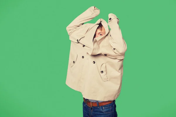 Young man wearing jacket while looking from jacket over green background