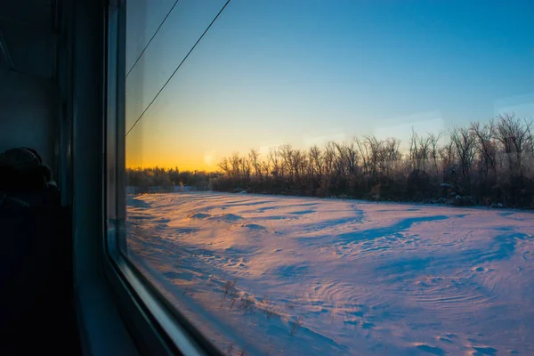 forests and fields in the rays of dawn through the window of a speeding train