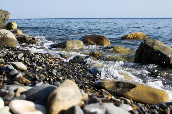 黒海とそれらから飛び散るダストの海岸に横になっている石に対して衝突青い波 — ストック写真