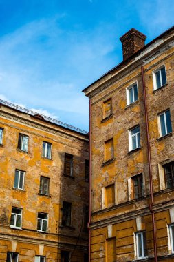 çatıda bir baca ile eski, sarı, eski, eski ve kırık çok katlı bina