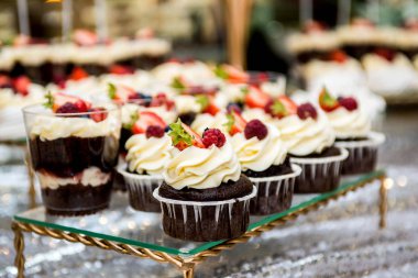 çay masası, krem, çilek ve yaban mersini ile güzel, parlak ve lezzetli cupcakes-cupcakes bir sürü