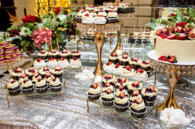 çay masası, krem, çilek ve yaban mersini ile güzel, parlak ve lezzetli cupcakes-cupcakes bir sürü