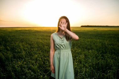 Genç, güzel Asyalı kız gün batımında yeşil buğday tarlasında