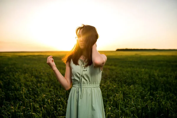 Genç, güzel Asyalı kız gün batımında yeşil buğday tarlasında